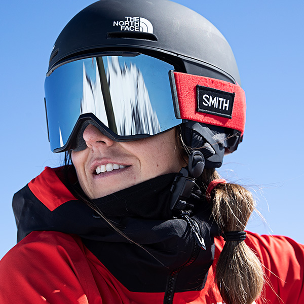 Woman smiling in a black Smith and The North Face Helmet and red Smith Goggles