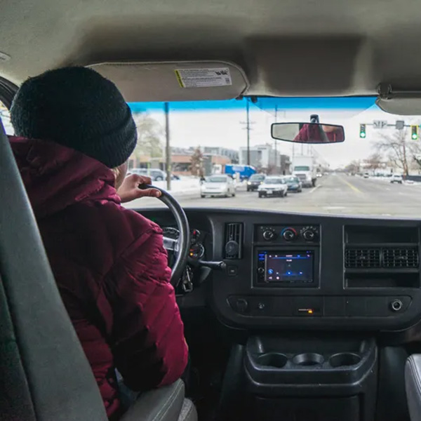 view of a man from behind driving a van wearing a red puffy coat