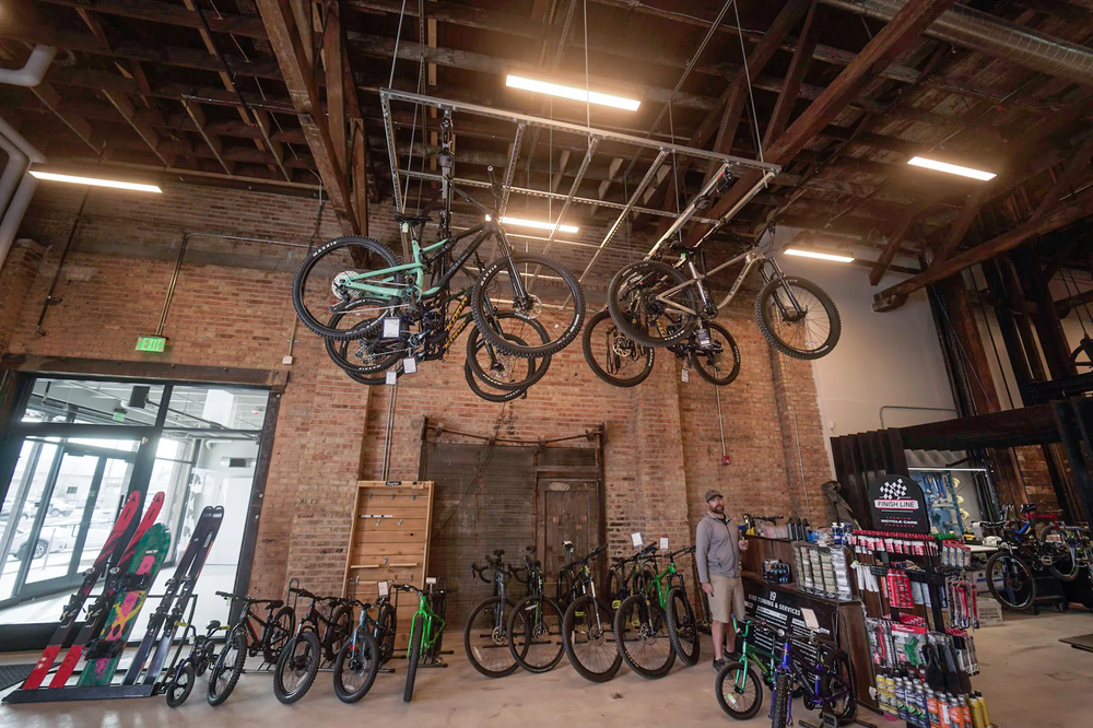 Bikes hanging from a high ceiling while more are displayed on the floor below them.