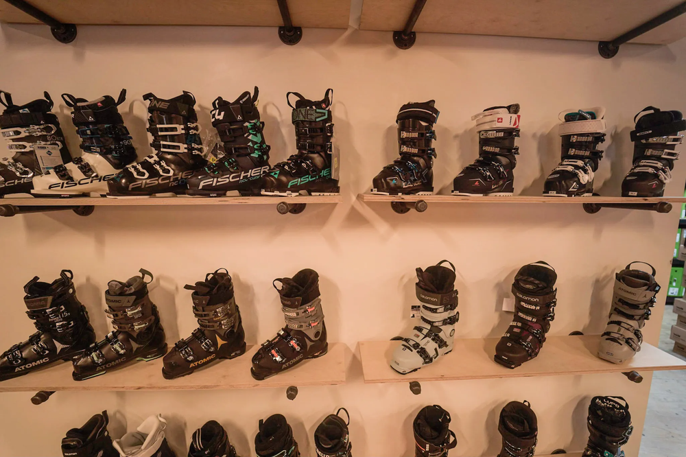 Ski boots on display, 4 shelves hold a range of different ski boots in a retail setting.