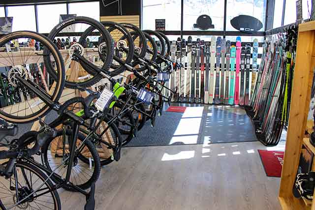 Bikes are hanging on a rack to the left while skis are on display in front and on the right.