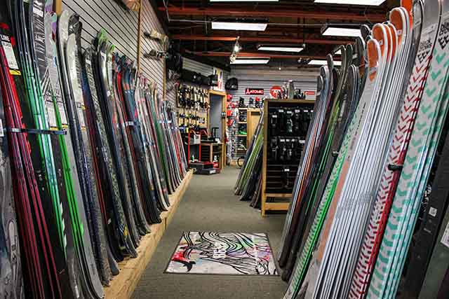 A view of flat skis line either side of an aisle.
